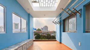 A room with a skylight, a balcony with a metal railing, and a view of buildings in the distance.