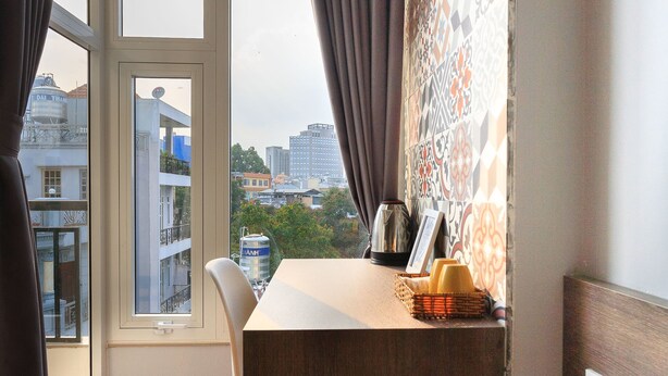 A room with a view of the city, a dining table with chairs, a vase with flowers, and a window with curtains.