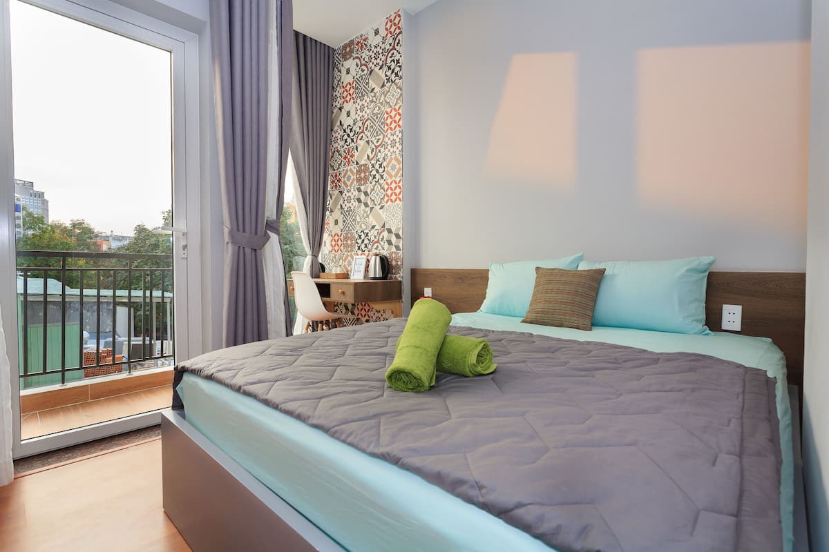 Een hotelkamer met een bed, een bureau en uitzicht op de stad door een groot raam.