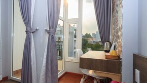 A room with a view of a cityscape through a large window, a table with a basket, and a chair.