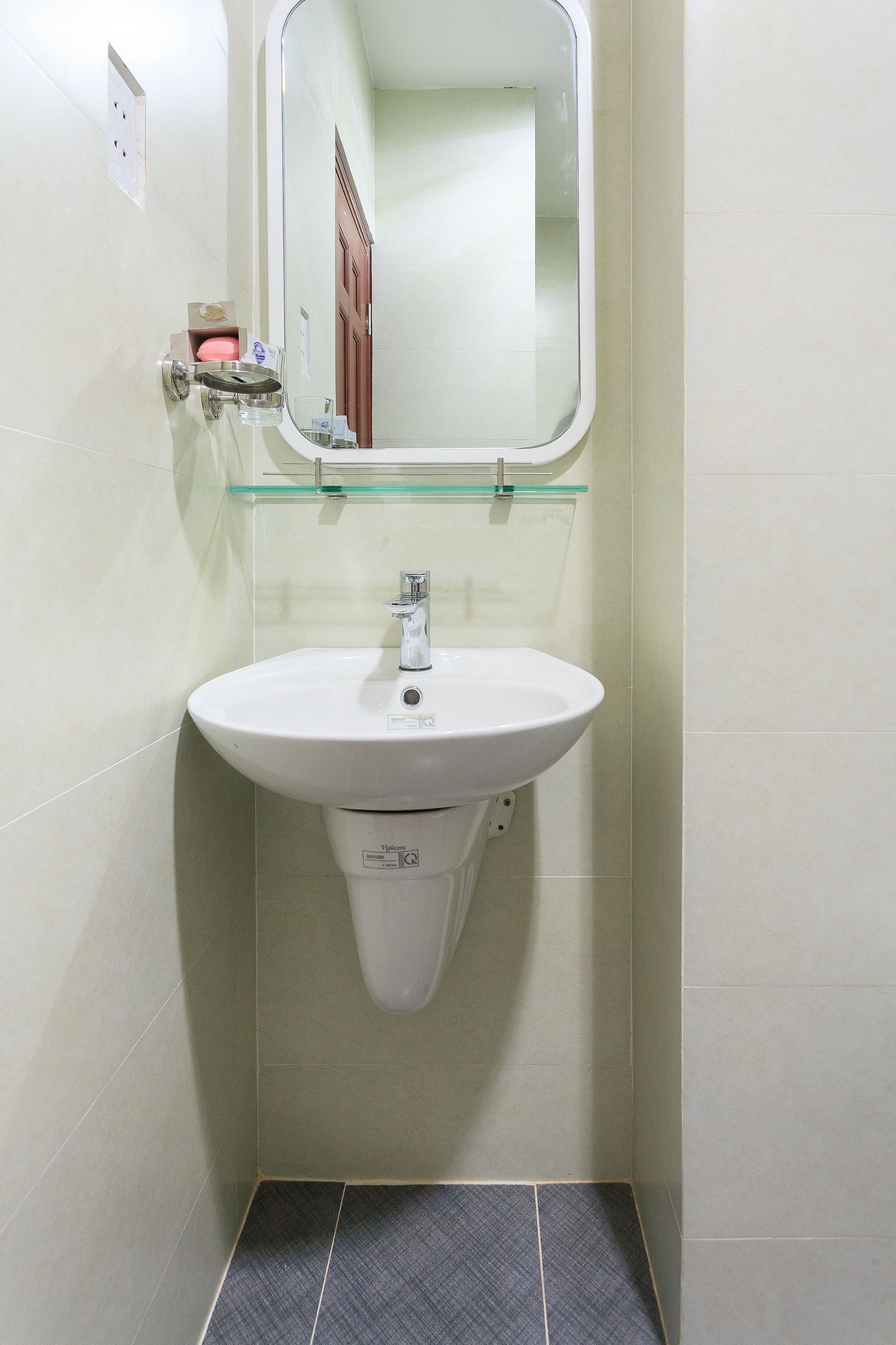 A bathroom with a white pedestal sink, a glass shelf above the sink, and a mirror.