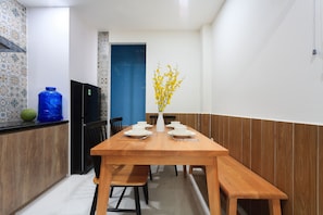 A dining area with a wooden table set for four, a blue water dispenser, and a vase with yellow flowers.