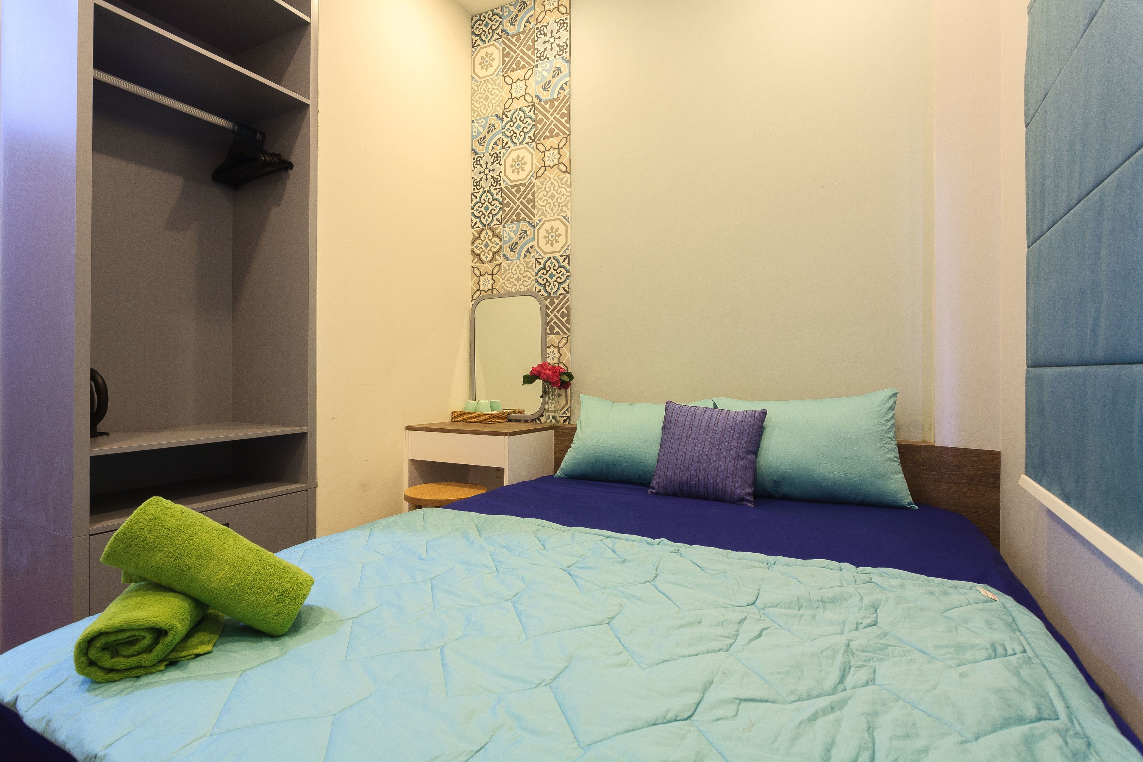 A bedroom with a bed, a nightstand, a mirror, and a wardrobe.