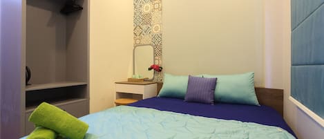 A bedroom with a bed, a nightstand, a mirror, and a wardrobe.