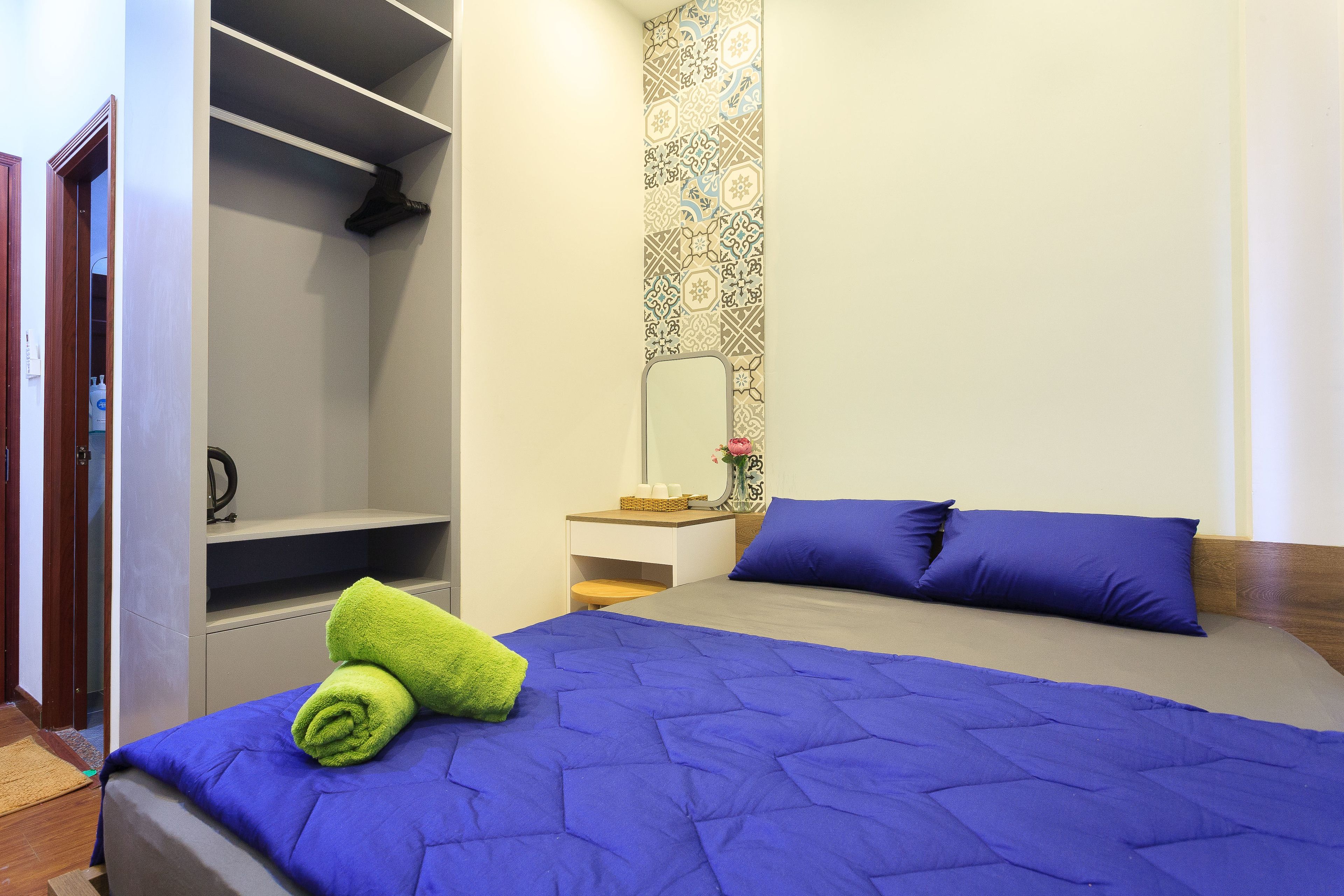 Een slaapkamer met een bed, nachtkastje, spiegel en garderobe.