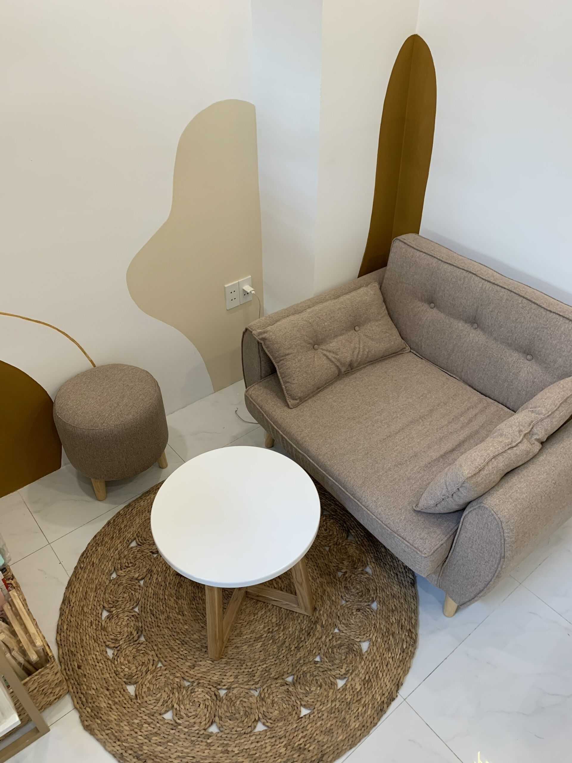 A modern living room with a grey sofa, a round white coffee table, and a woven rug.