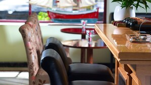 A dining area with a table, chairs, a potted plant, and a view of a sailboat outside.
