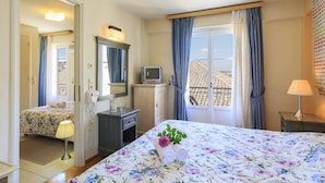 A hotel room with a bed, a desk, a TV, and a window with curtains.