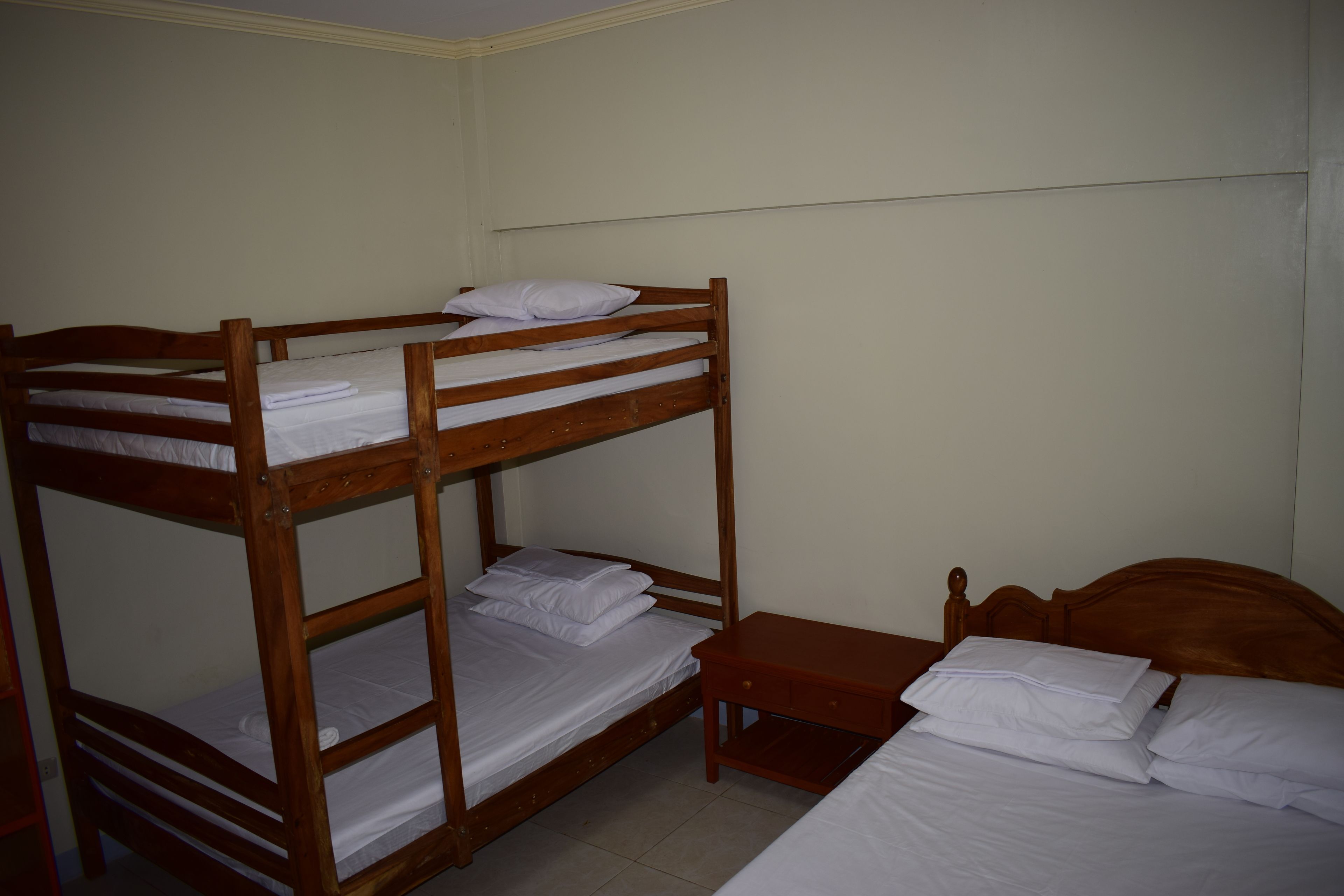 A bunk bed room with a wooden headboard, a wooden nightstand, and a single bed.