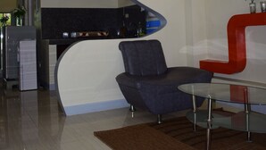 A modern living room with a curved white and red sofa, a glass coffee table, and a kitchen in the background. - Villa d' Arco Resort (Santa Cruz)