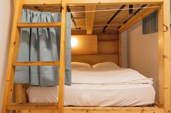 Una habitación pequeña de madera con una litera, una escalera y una cortina.