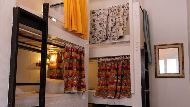 Habitación tipo dormitorio con literas, una cortina, un espejo y una puerta con un número.