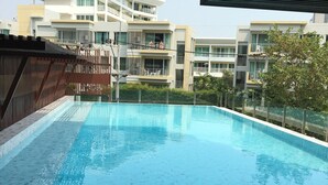 A swimming pool with a tiled deck, surrounded by a fence and a view of multi-story buildings. - Rocco Hua Hin 512 Condominium (Hua Hin)