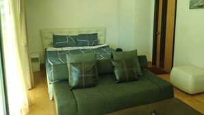A bedroom with a bed, a sofa, and a door. - Rocco Hua Hin 512 Condominium (Hua Hin)