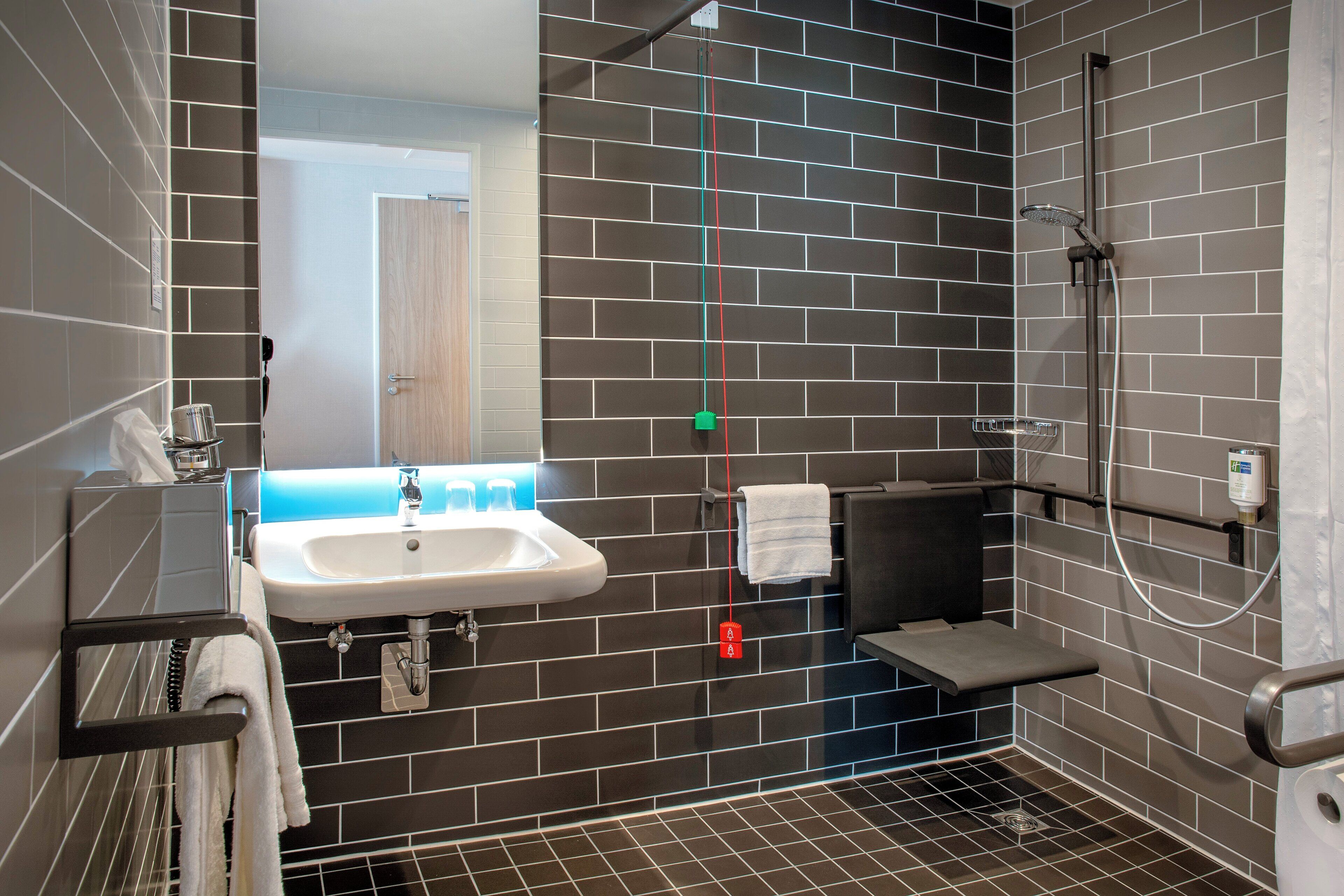 A modern bathroom with a sink, mirror, towel rack, and shower.