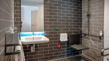 Ein modernes Badezimmer mit Waschbecken, Spiegel, Handtuchhalter und Dusche.