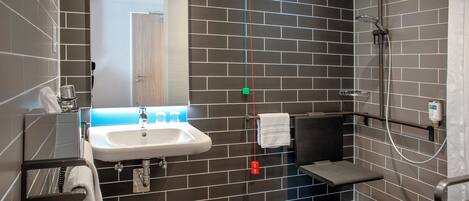 A modern bathroom with a sink, mirror, towel rack, and shower.