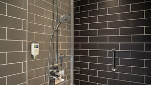 A shower area with a glass enclosure, a handheld showerhead, and a handheld shower attachment.