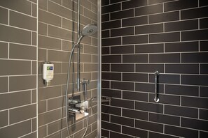 A shower area with a glass enclosure, a handheld showerhead, and a handheld shower attachment.