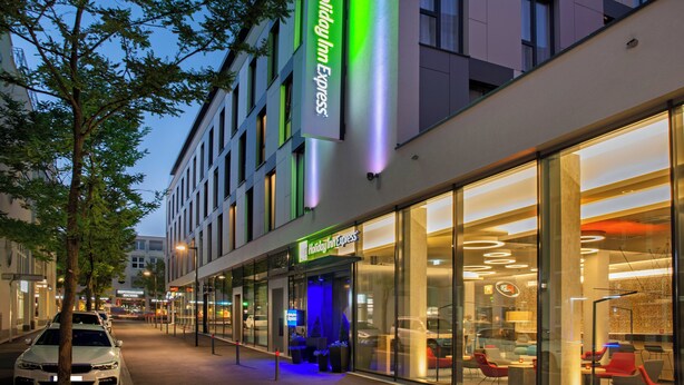 A modern building with a Holiday Inn Express sign, large glass windows, and a visible entrance.