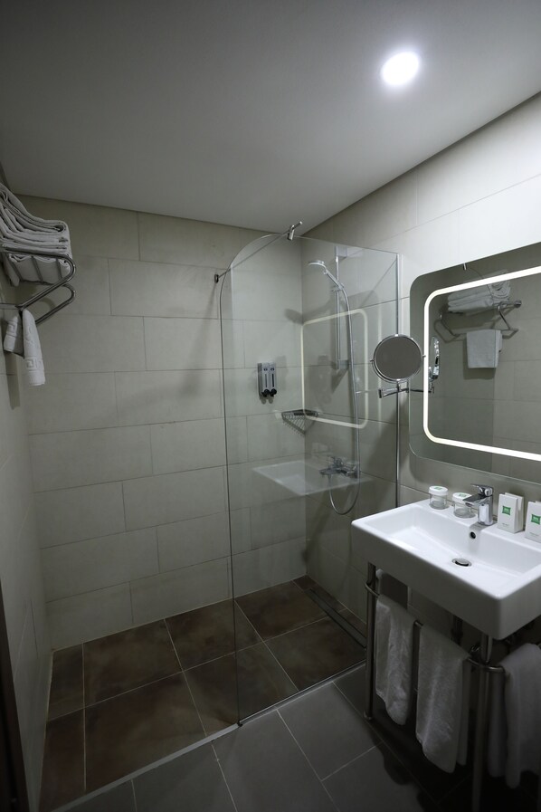 A modern bathroom with a glass-enclosed shower, a white sink with a mirror, and neatly arranged towels.