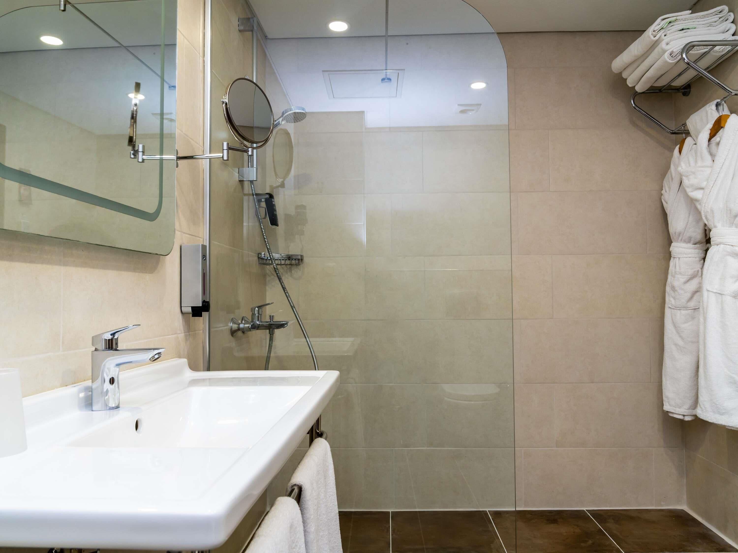 A modern bathroom with a glass-enclosed shower, a white sink, and a mirror.