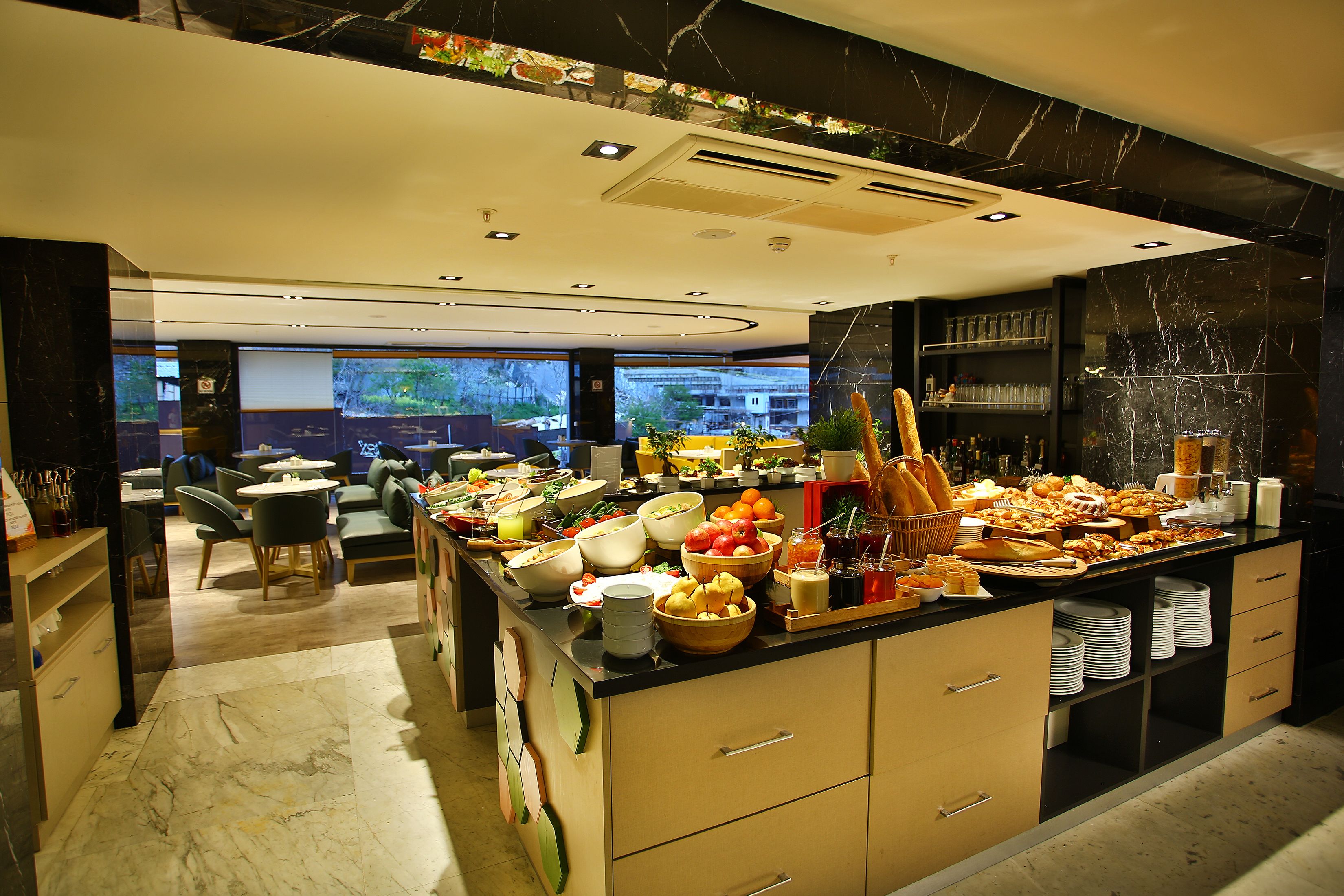 A modern kitchen with a buffet setup, marble flooring, and a view of the outside.