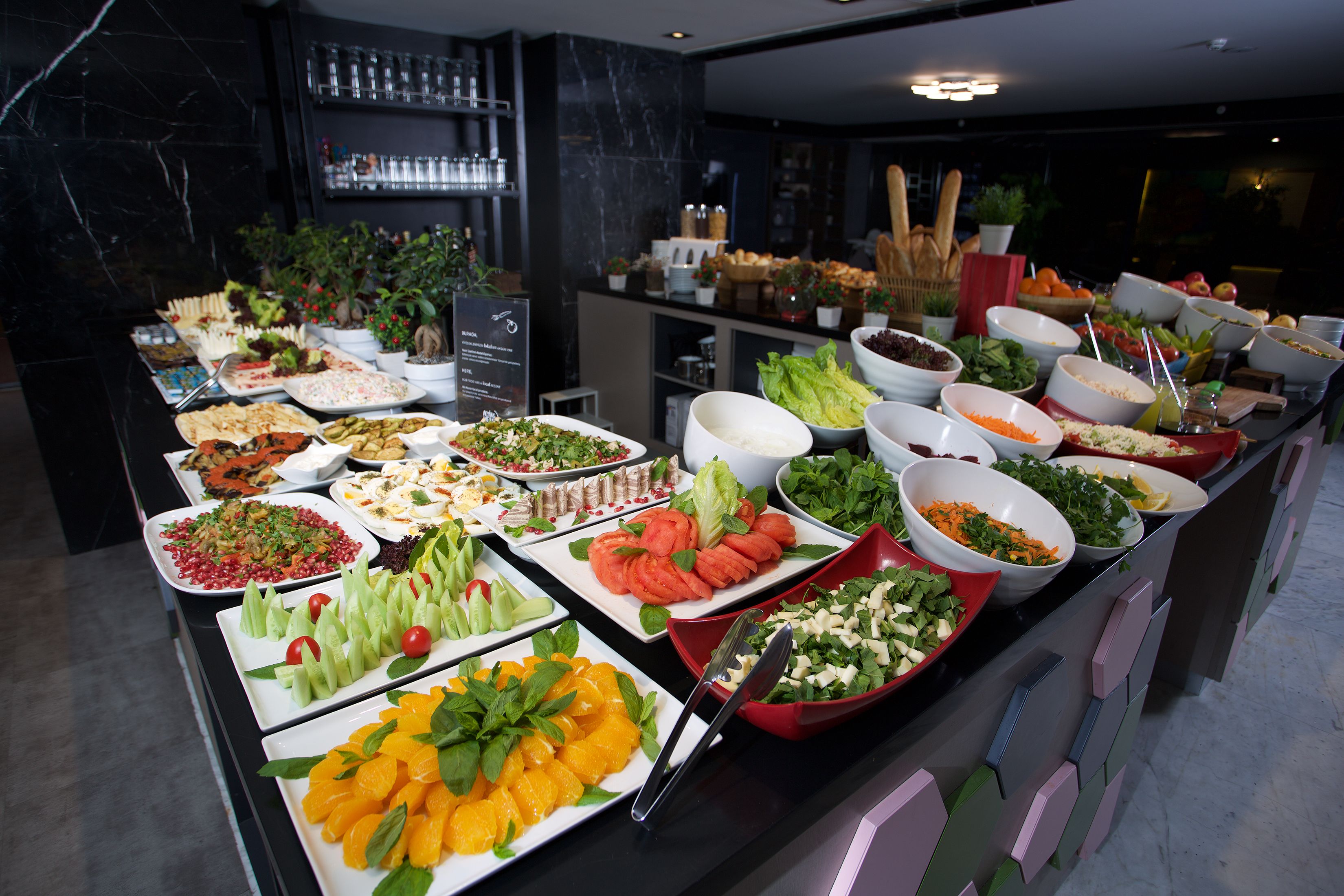 A buffet with various dishes and a marble wall in the background.