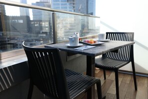 A modern dining area with a table and chairs, a city view through a glass railing, and a tray of macarons. - ibis Styles Istanbul Bomonti (Istanbul)