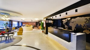 A modern hotel lobby with a reception desk, seating area, and a world map mural. - ibis Styles Istanbul Bomonti (Istanbul)