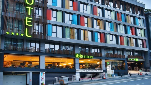 A hotel with a modern design, featuring multiple floors and large windows. The hotel has a sign that reads "ibis Styles" and another sign indicating "PROFESYONEL KOZMETIK MARKETİ". - ibis Styles Istanbul Bomonti (Istanbul)