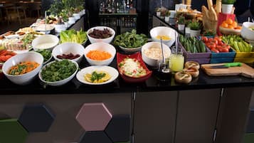 A buffet with various food items and a bar area with bottles and glasses.
