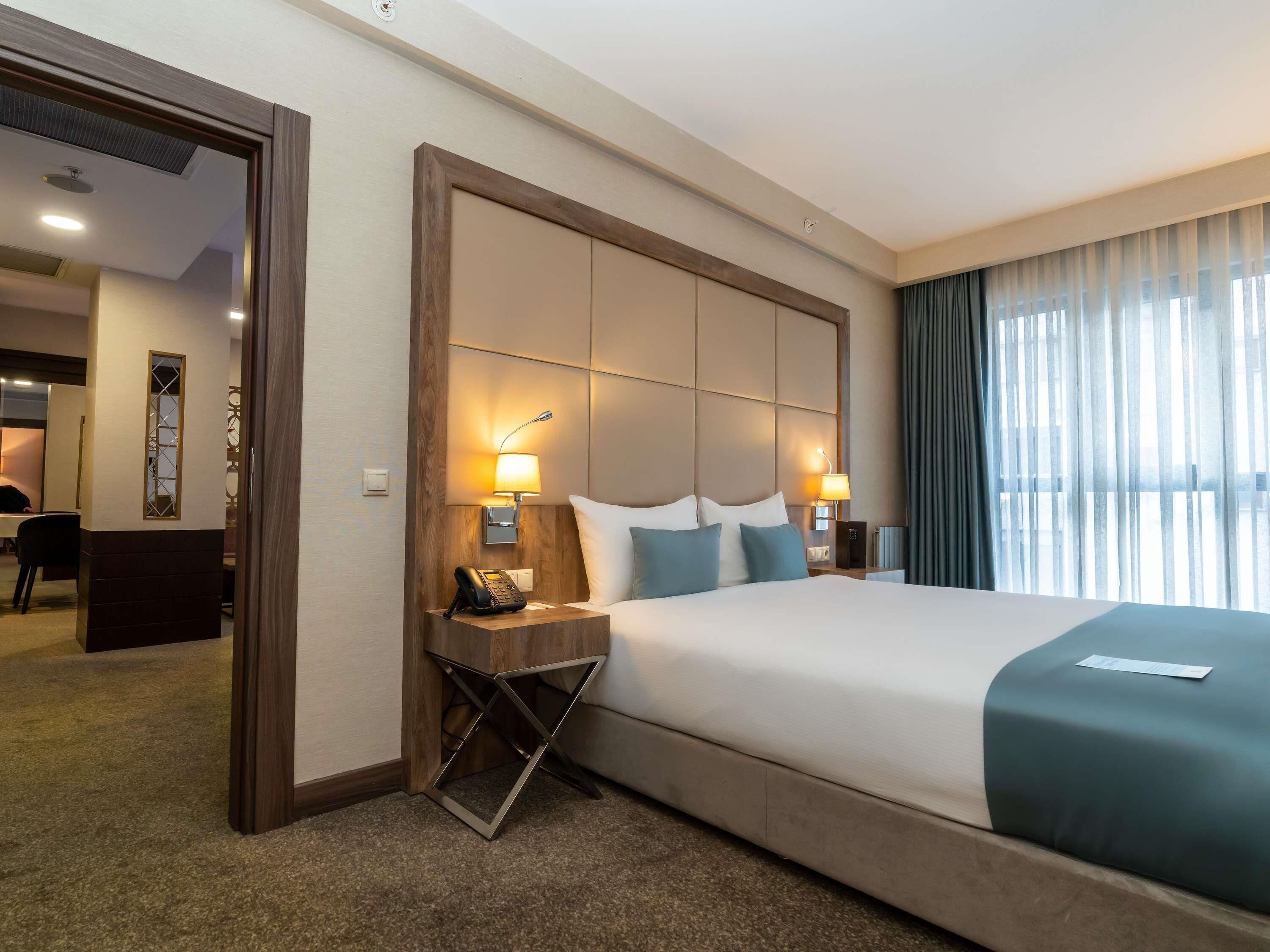Une chambre d’hôtel avec un grand lit, deux tables de chevet avec des lampes, un bureau et une chaise.