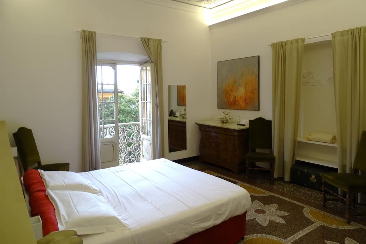 A hotel room with a bed, a desk, a chair, a dresser, and a painting on the wall.