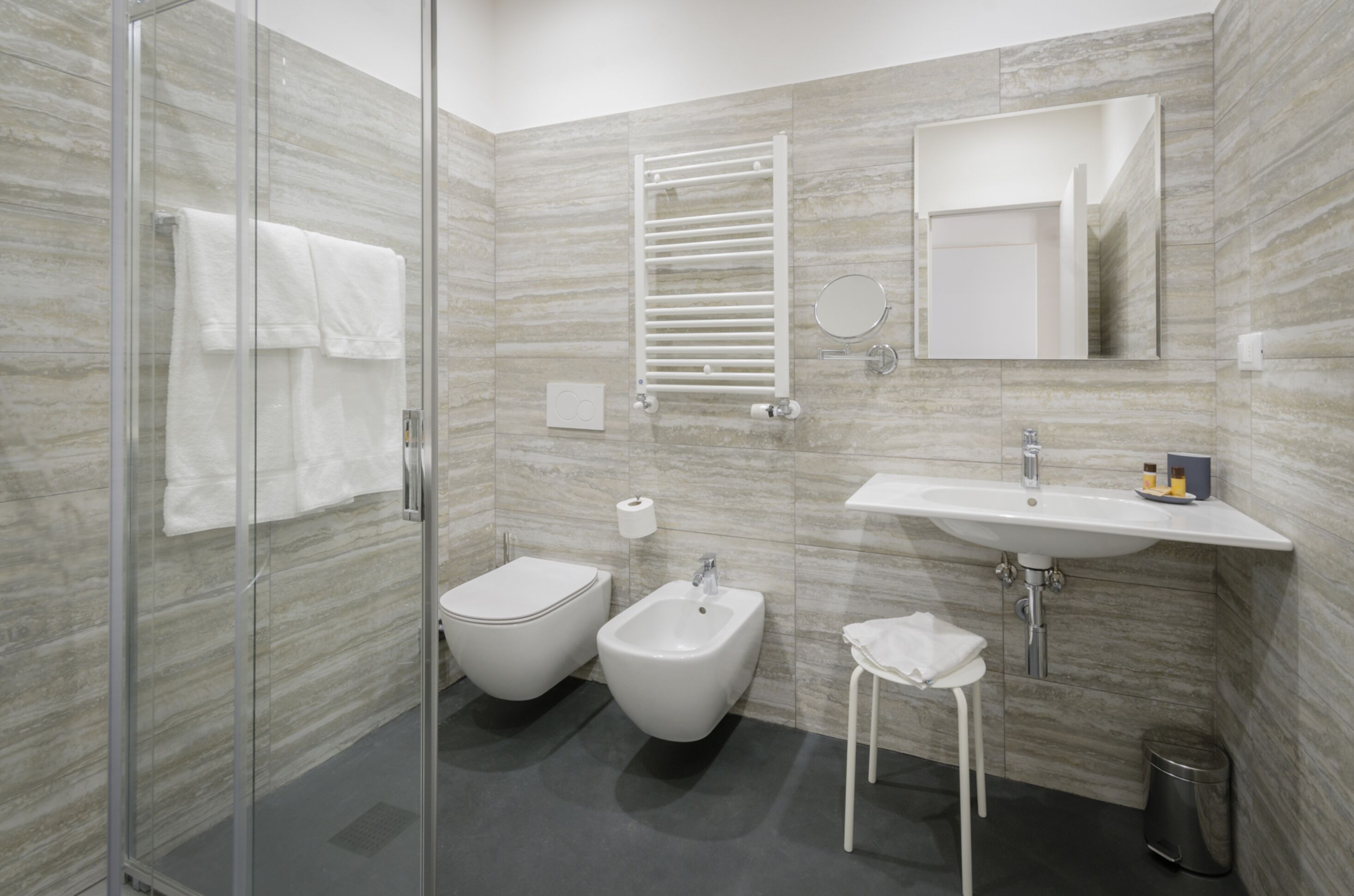 Een moderne badkamer met een douchecabine van glas, een toiletbril met douchefunctie, een wastafel en een spiegel.