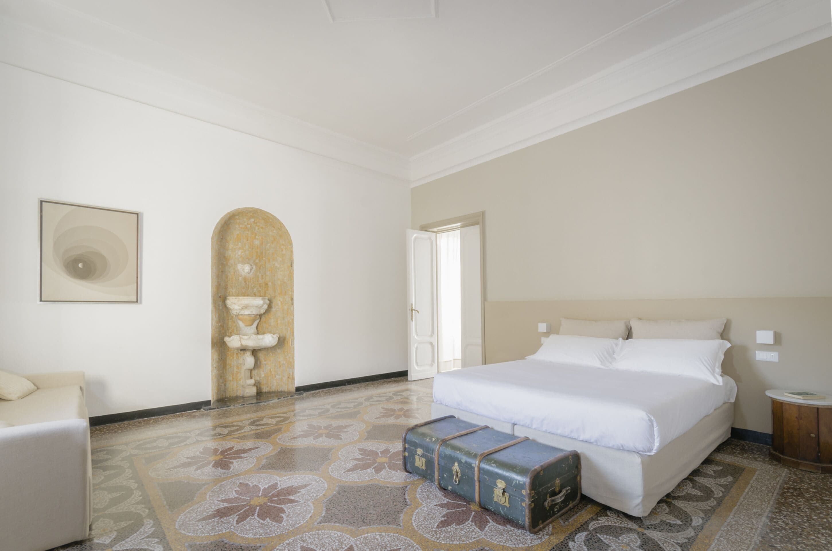 Une chambre à coucher avec un grand lit, une commode, une chaise et une fontaine décorative.