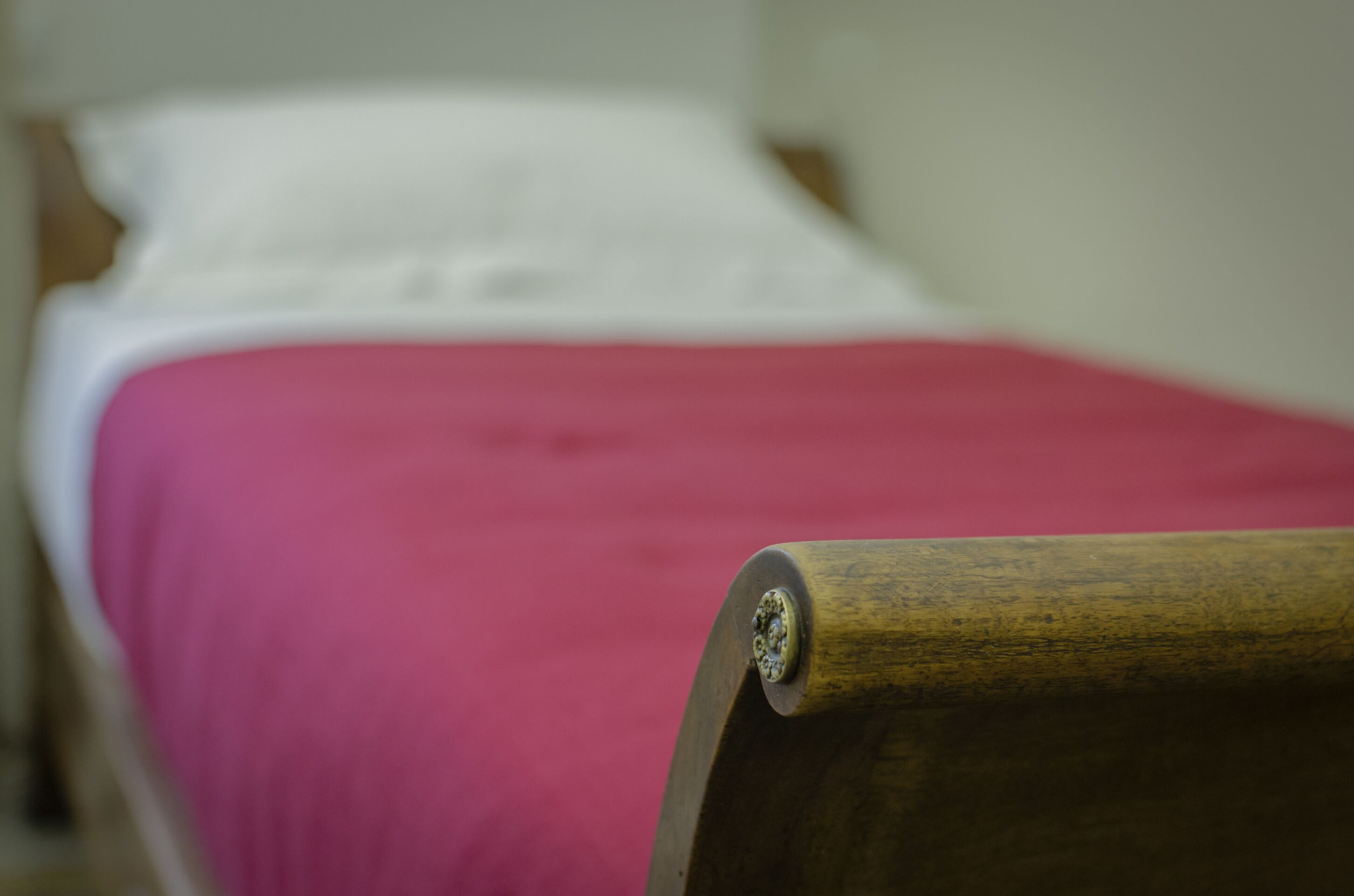 A bed with a wooden headboard and a pink bedspread.