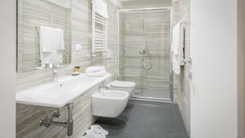 A modern bathroom with a large mirror, white fixtures, a shower, and a bidet.