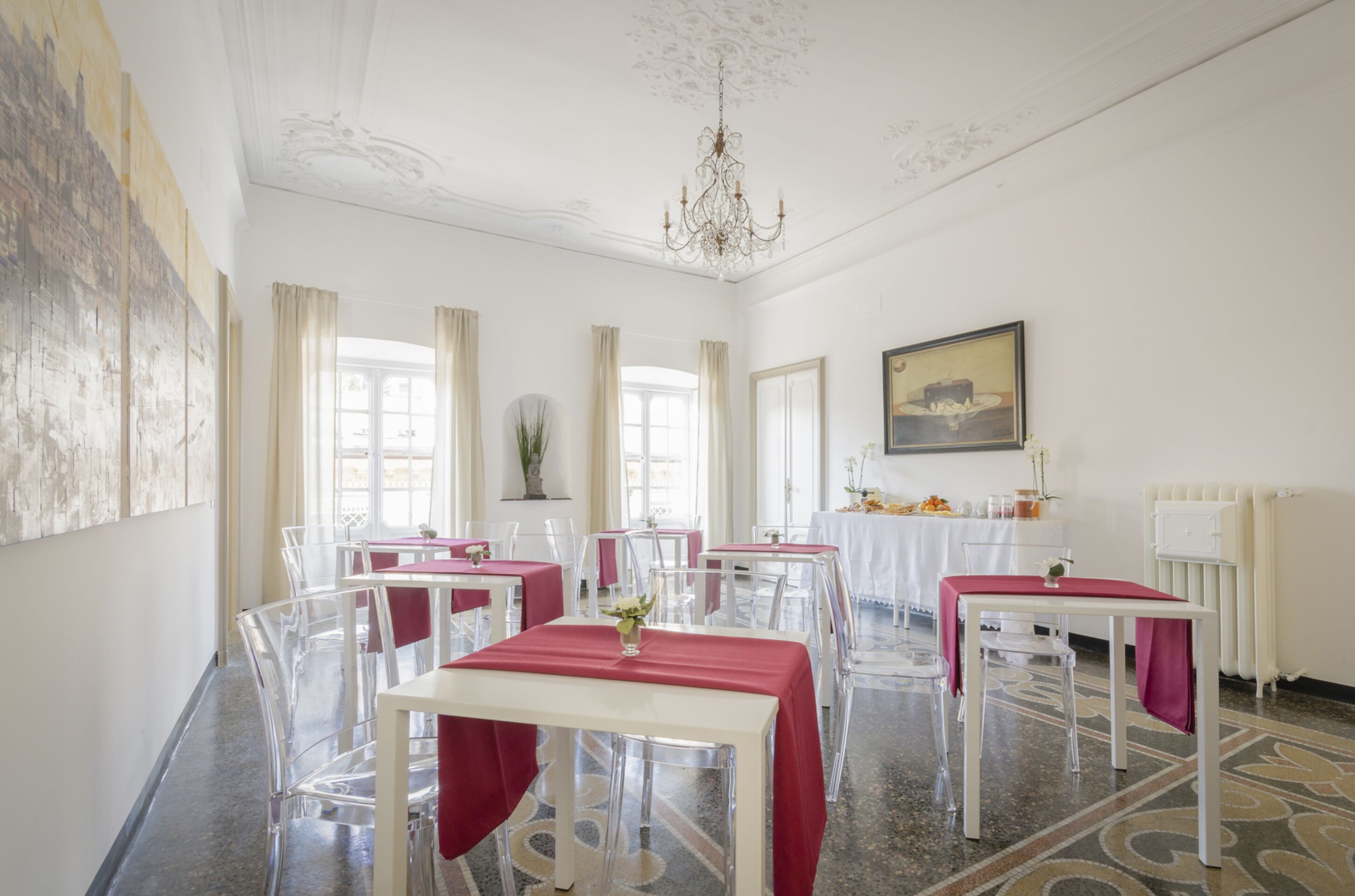 Un comedor con mesas dispuestas para los invitados, sillas despejadas y una araña.