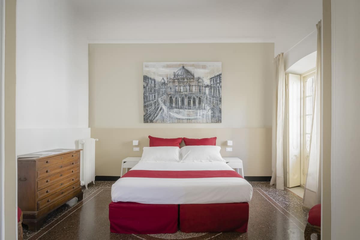 A hotel room with a large bed, a wooden dresser, and a painting on the wall.