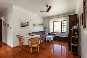 Uma área de refeições com uma mesa redonda, cadeiras de vime e um ventilador de teto.