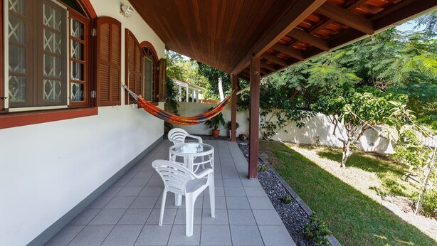 Un patio cubierto con sillas blancas y una hamaca.