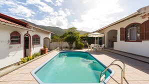 Una piscina rectangular con una escalera metálica, rodeada por un patio con baldosas.