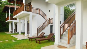 A multi-story building with a white exterior, wooden balconies, and a staircase. - Nature Paradise Villas (Balapitiya)