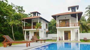 A two-story house with a swimming pool, surrounded by lush greenery and palm trees. - Nature Paradise Villas (Balapitiya)