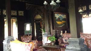 A spacious lobby with high ceilings, ornate wooden furniture, and a large painting on the wall. - Joglo Java (Semarang)