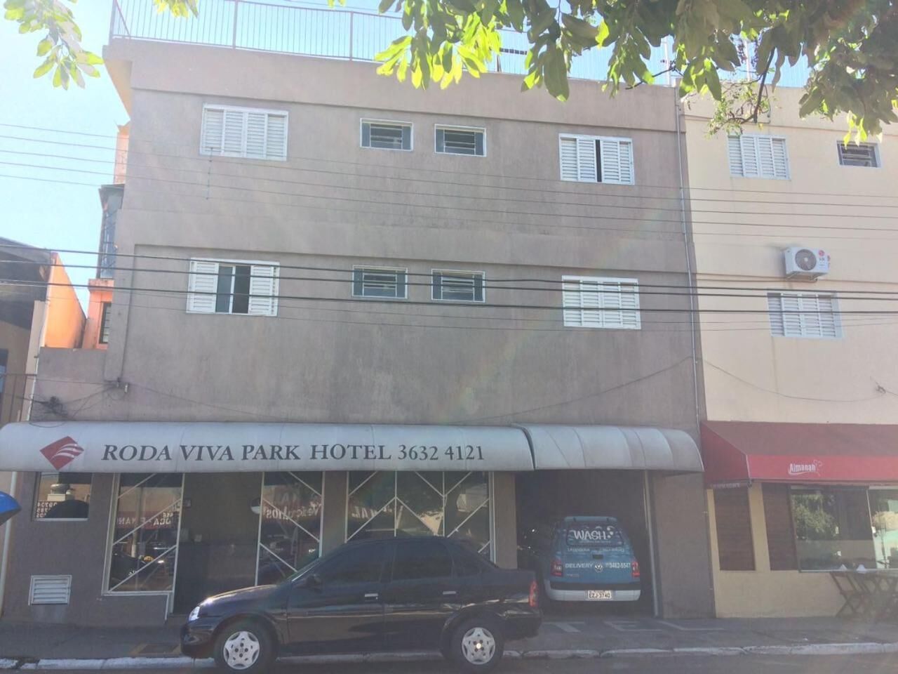A building with a sign for Roda Viva Park Hotel, featuring a car parked in front.