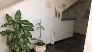A hallway with two potted plants, a tiled floor, and a wall-mounted electrical box. - Roda Viva Park Hotel (Jales)