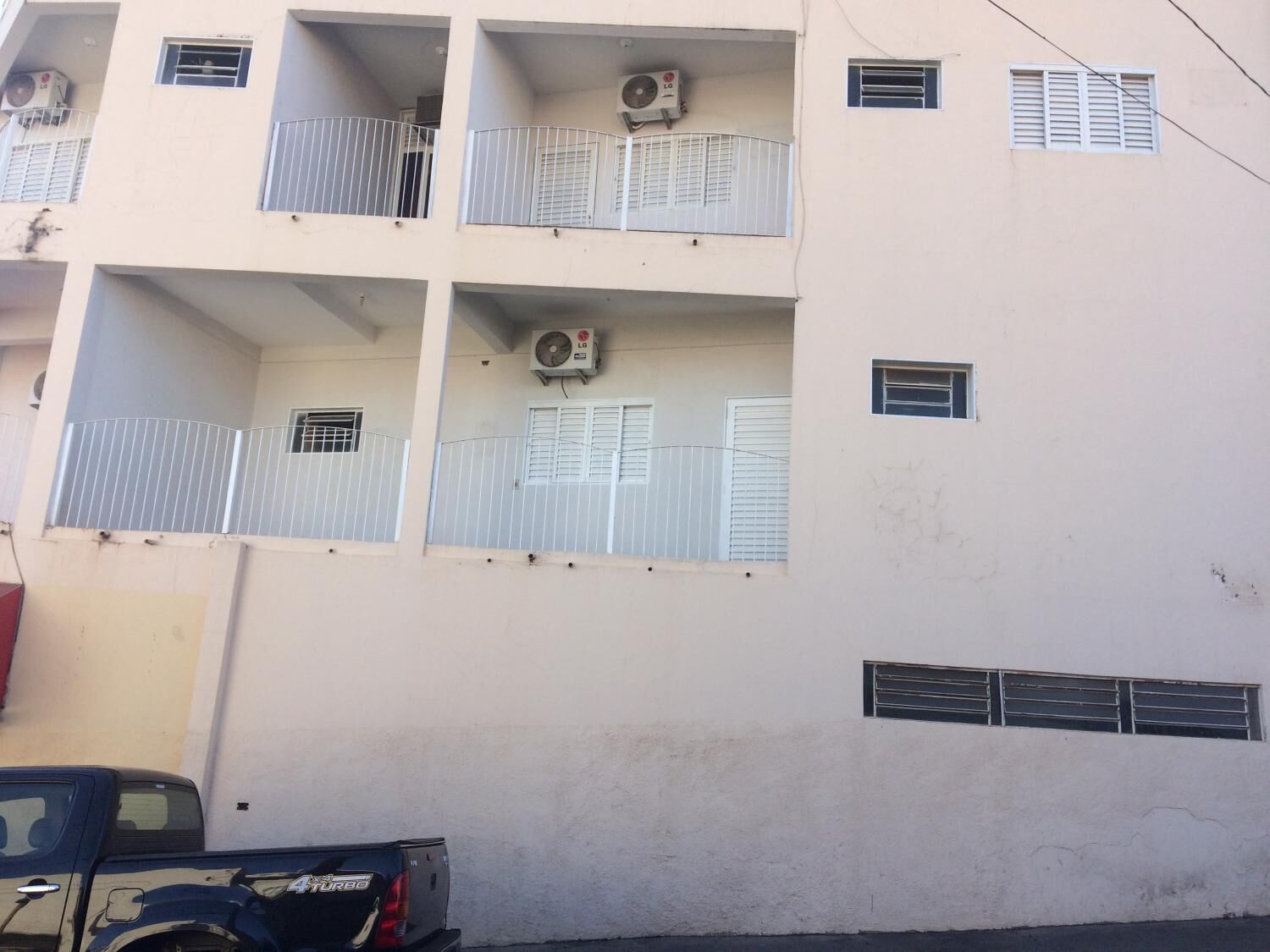 A multi-story building with balconies, air conditioning units, and a gated entrance.