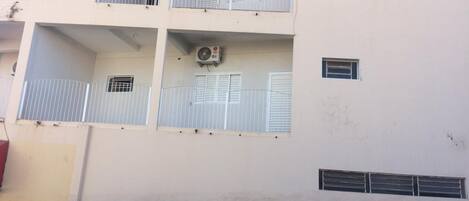 A multi-story building with balconies, air conditioning units, and a gated entrance.